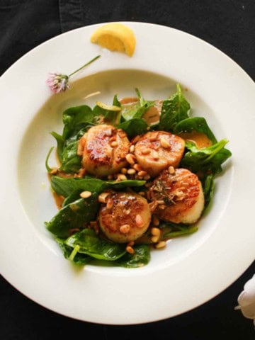 Seared Scallops with white wine butter sauce served over baby spinach.