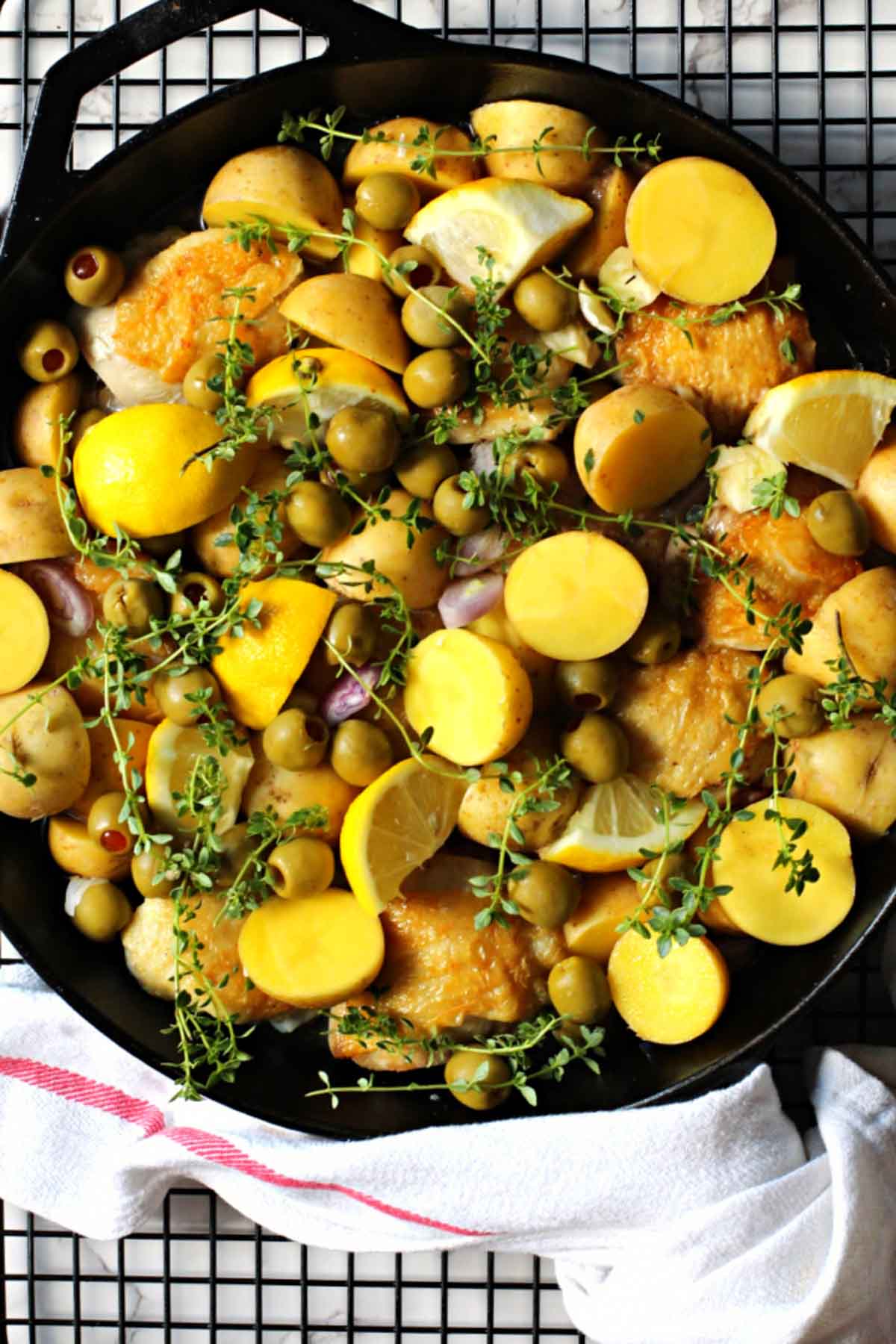 Yukon gold potatoes, chicken thighs, olives cooking in a cast iron skillet