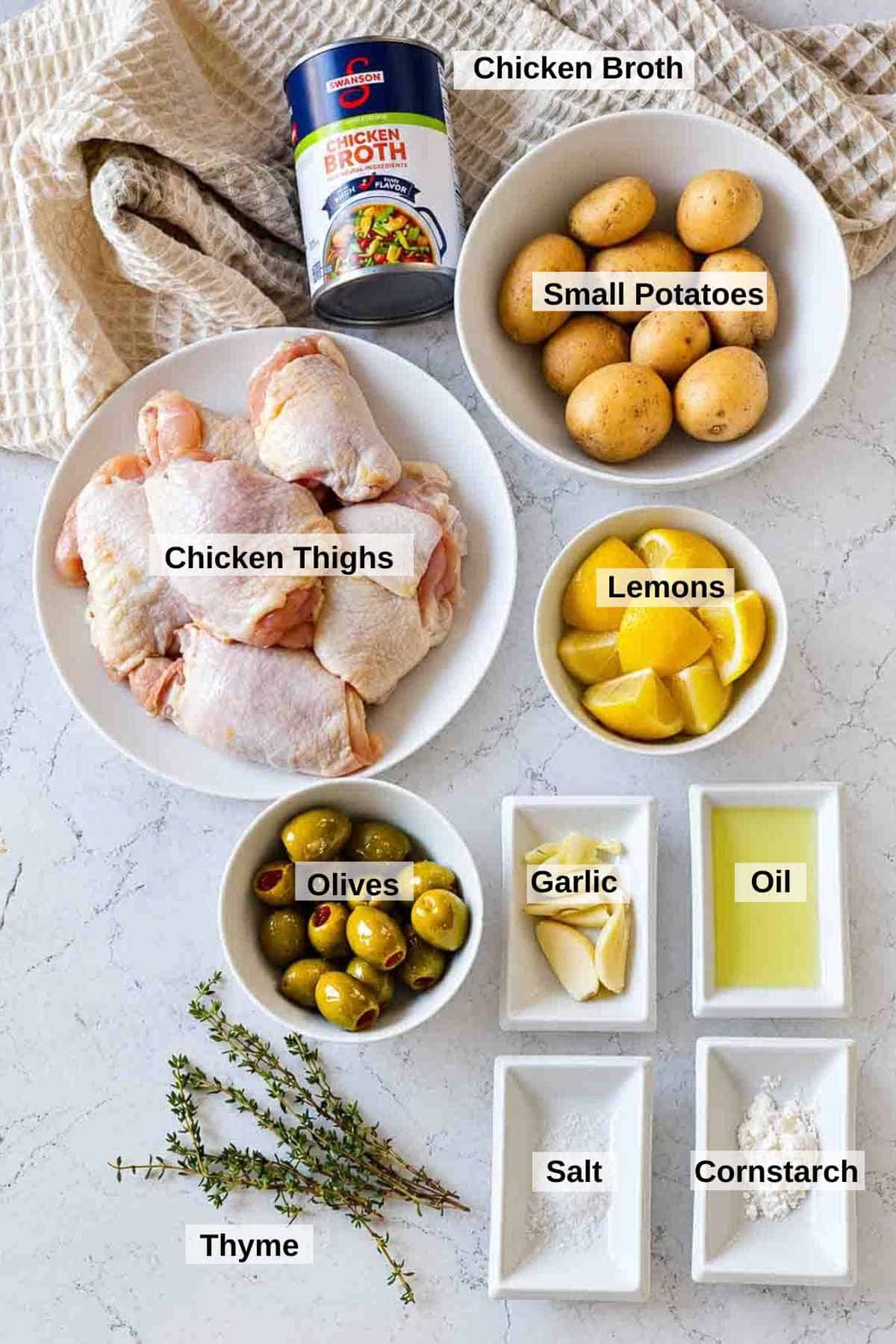 Ingredients to make braised chicken thighs with potatoes, lemon and olives.
