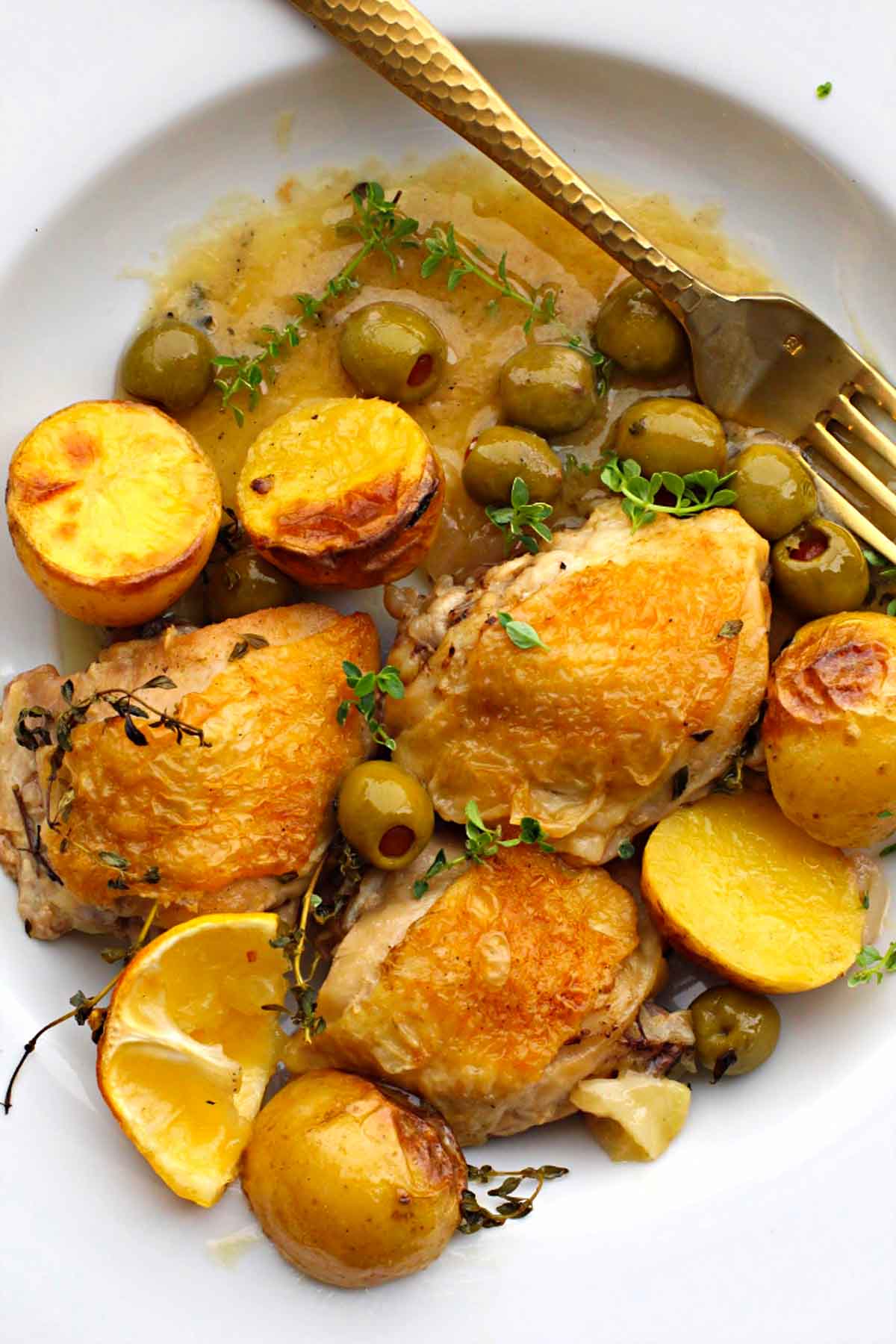 Cast iron skillet braised chicken thighs with potatoes and olives in a broth