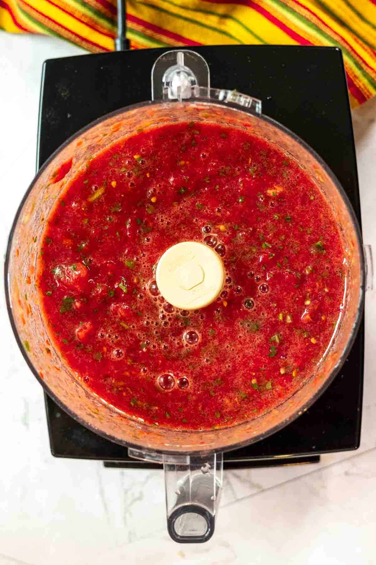 Chopped tomatoes and cilantro in a food processor to make freezer salsa.