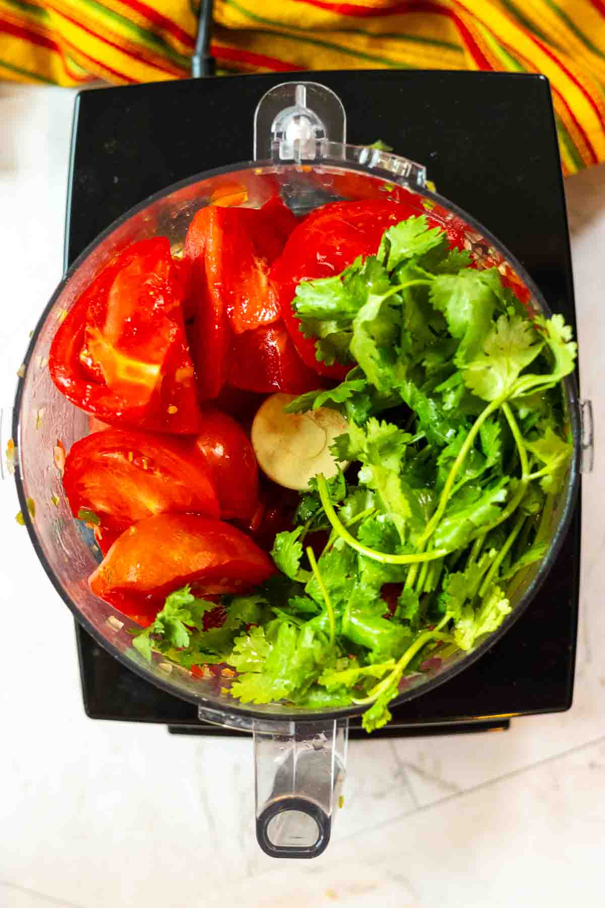 Chopping tomatoes and cilantro in a food processor to make freezer salsa.