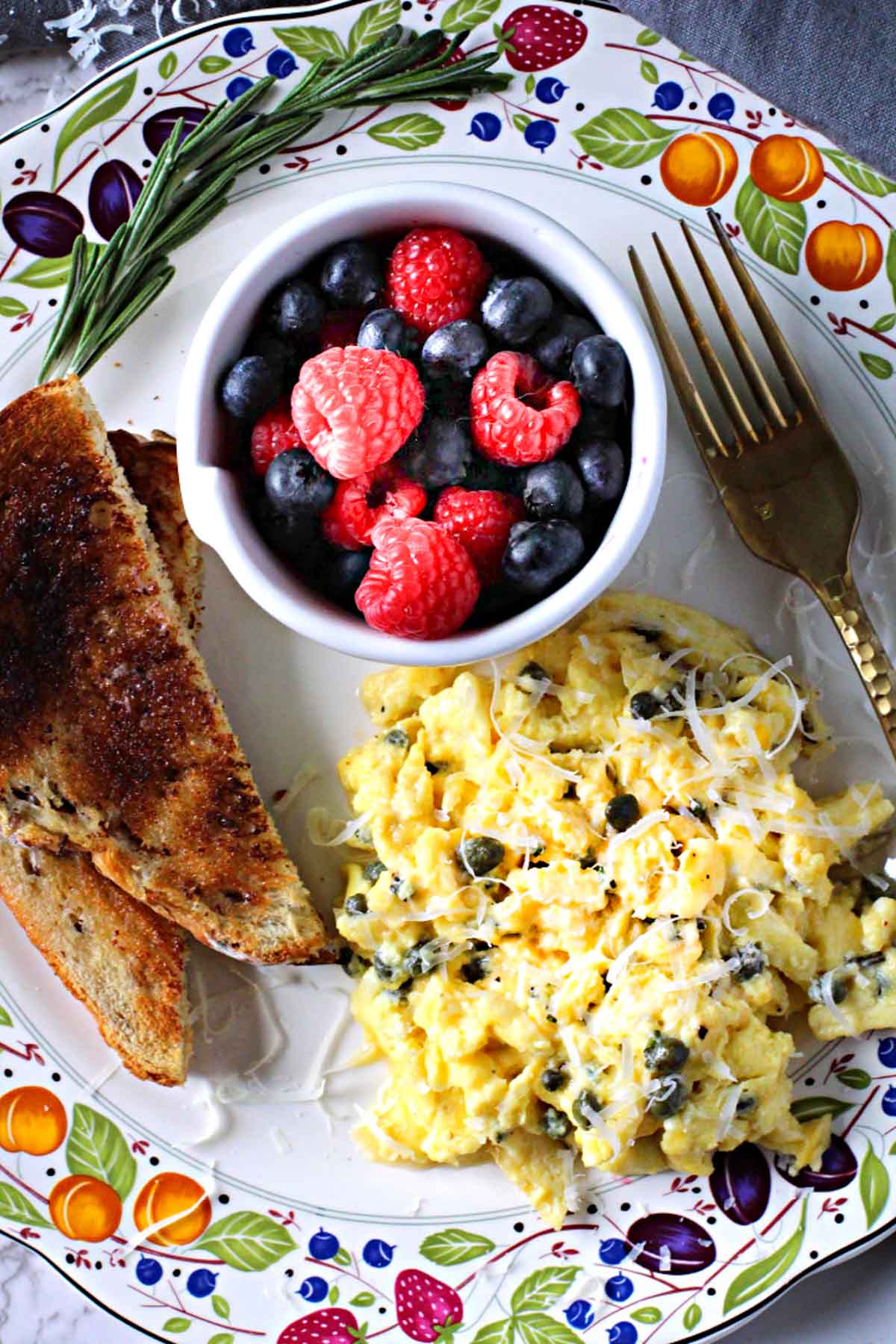 Scrambled eggs with capers served with toast and fresh berries