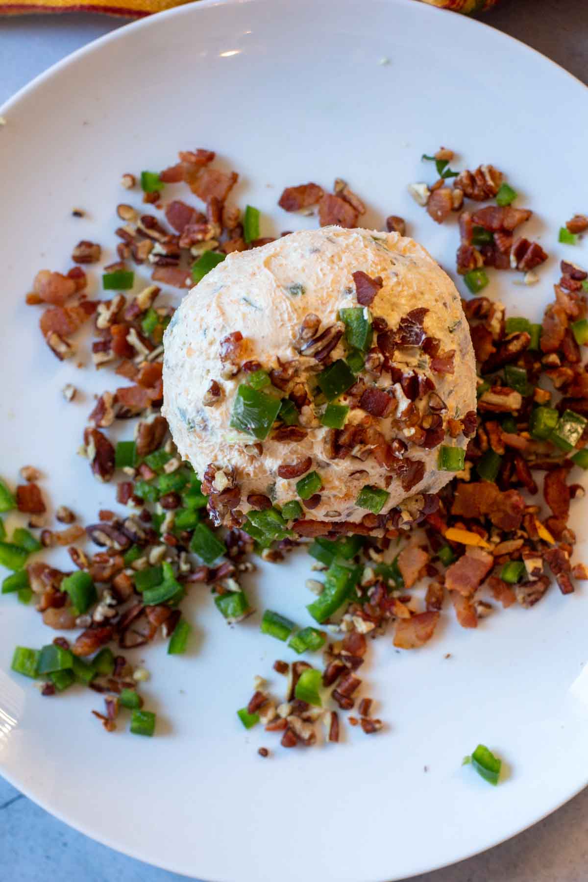 Rolling a cheeseball in jalapeno, bacon and pecans.