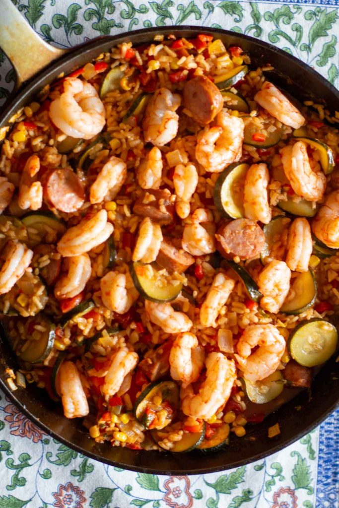 Arranging cooked shrimp on top of paella before serving.