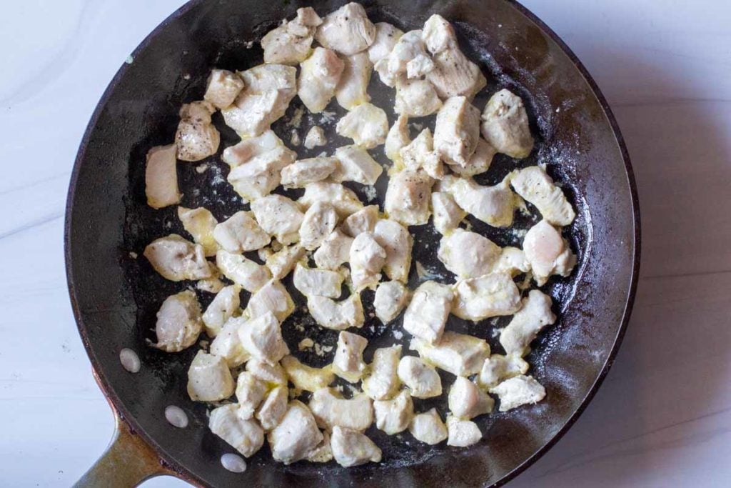 sauteeing chicken breast in a large black skillet