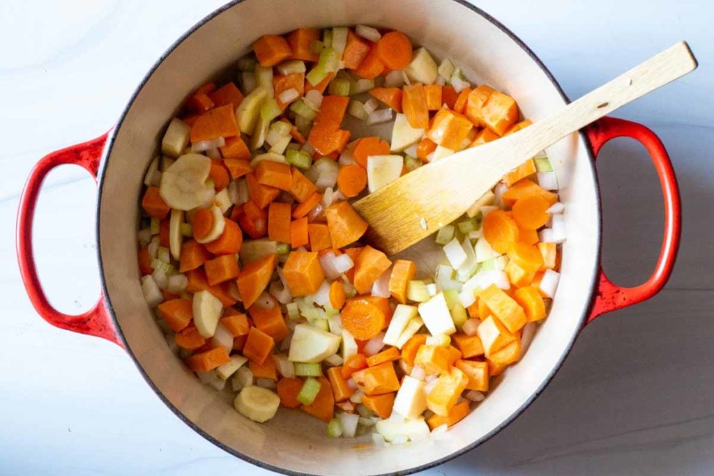 Sauteeing carrots, celery, onion, sweet potato and parsnip in a red le creuset dutch oven