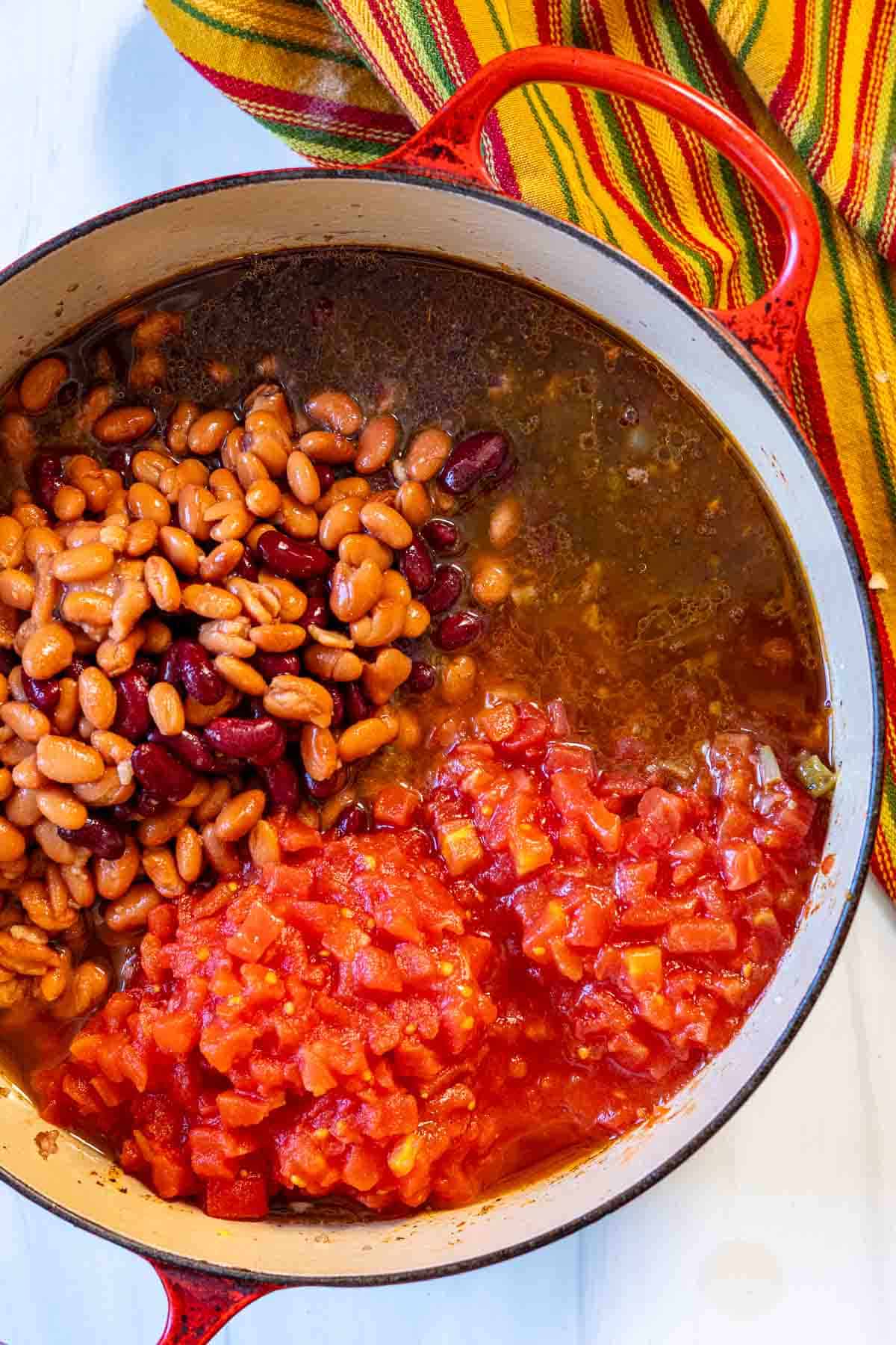 Adding beans and tomatoes to make award winning chili.