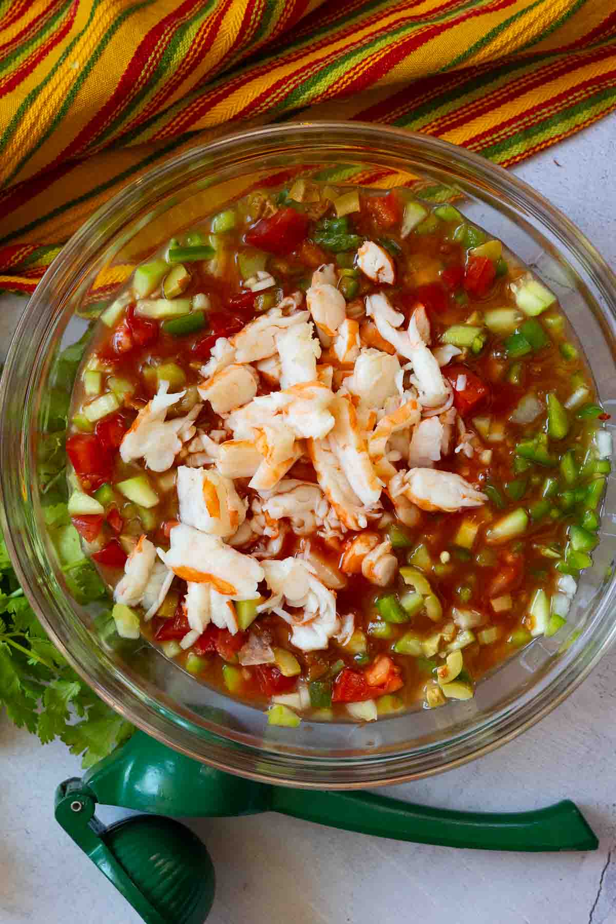 Step 4 to make campechana. Adding shrimp and tomato juice to vegetables.