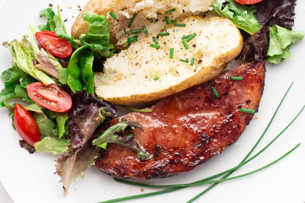 Grilled ham steak with baked potato and tossed salad