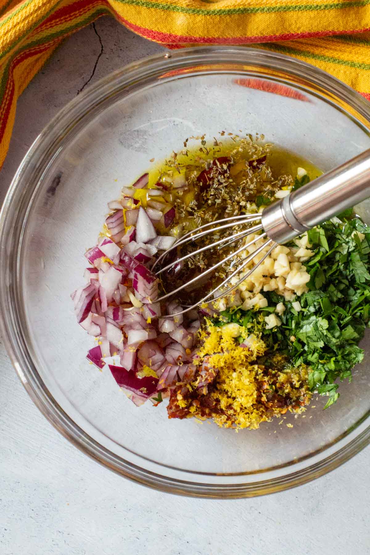 Chopped ingredients in a glass bowl to make flank steak chimichurri.