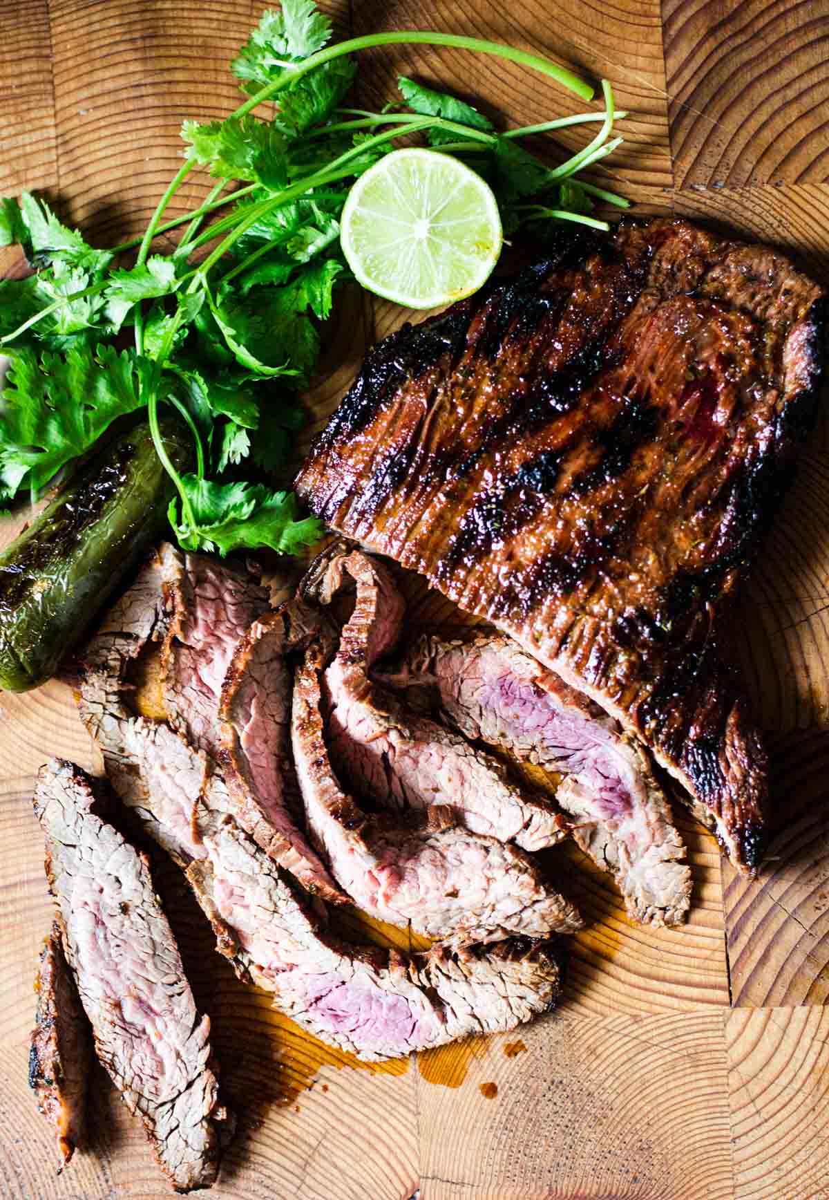 Grilled carne asada sliced and garnished with lime and cilantro.