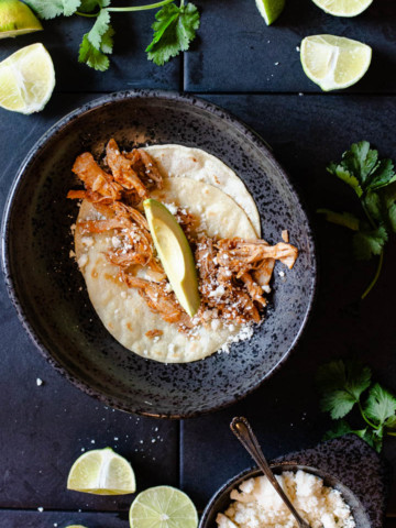 pork tacos on a soft corn tortilla topped with an avocado