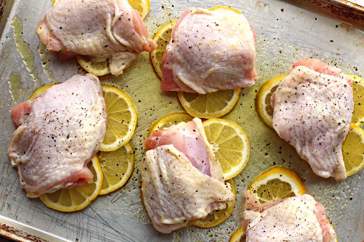 chicken thighs on a sheet pan with lemons and olive oil