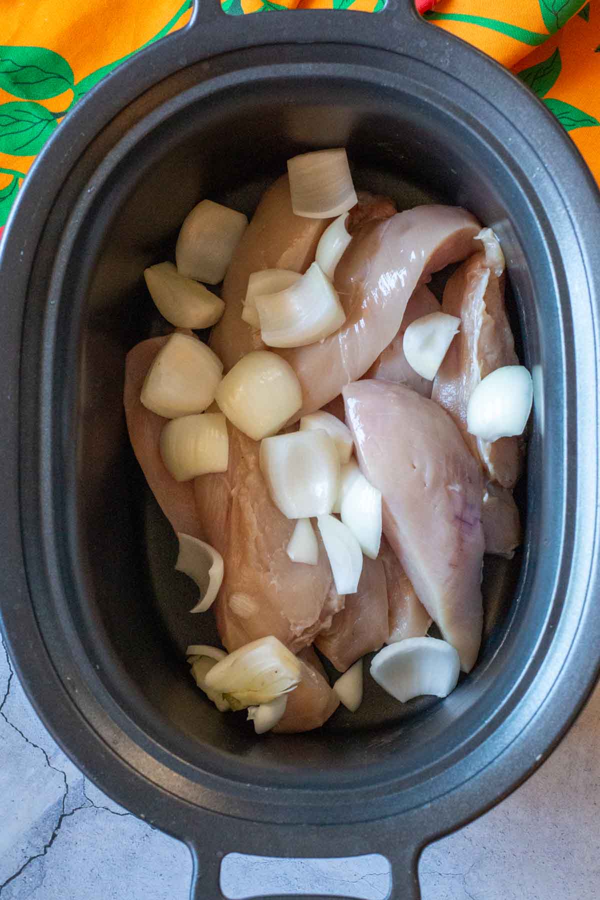 Chicken breasts and onions in a crockpot.