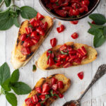 Toasted sliced baguettes topped with fresh tomatoes and chopped basil