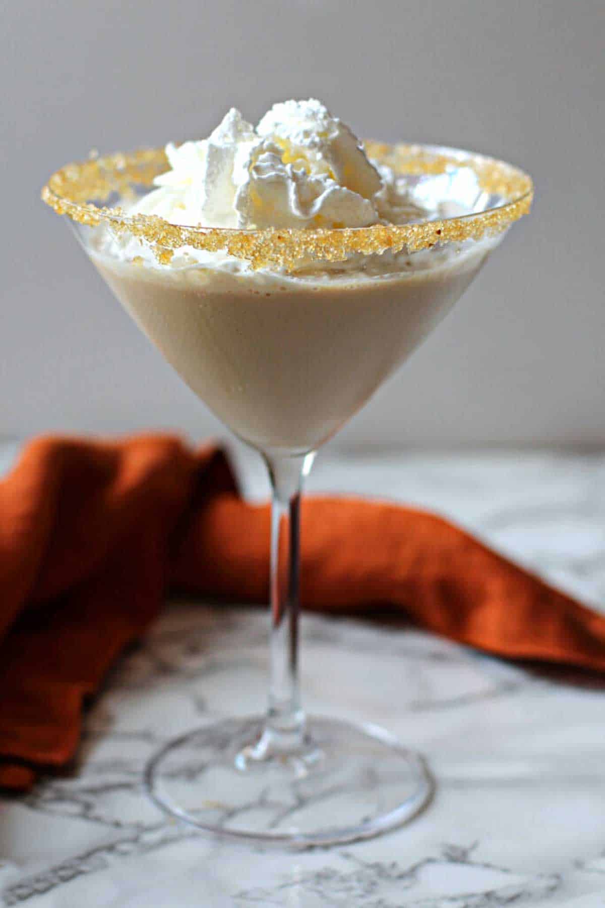 Pumpkin Martini Recipe served in a martini glass and topped with whipped cream.