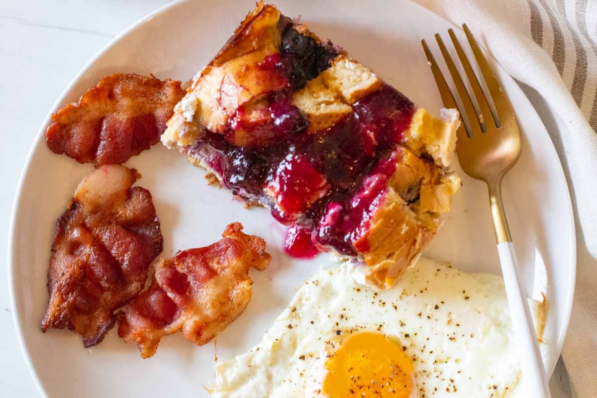 Blueberry french toast bake with bacon and a fried egg