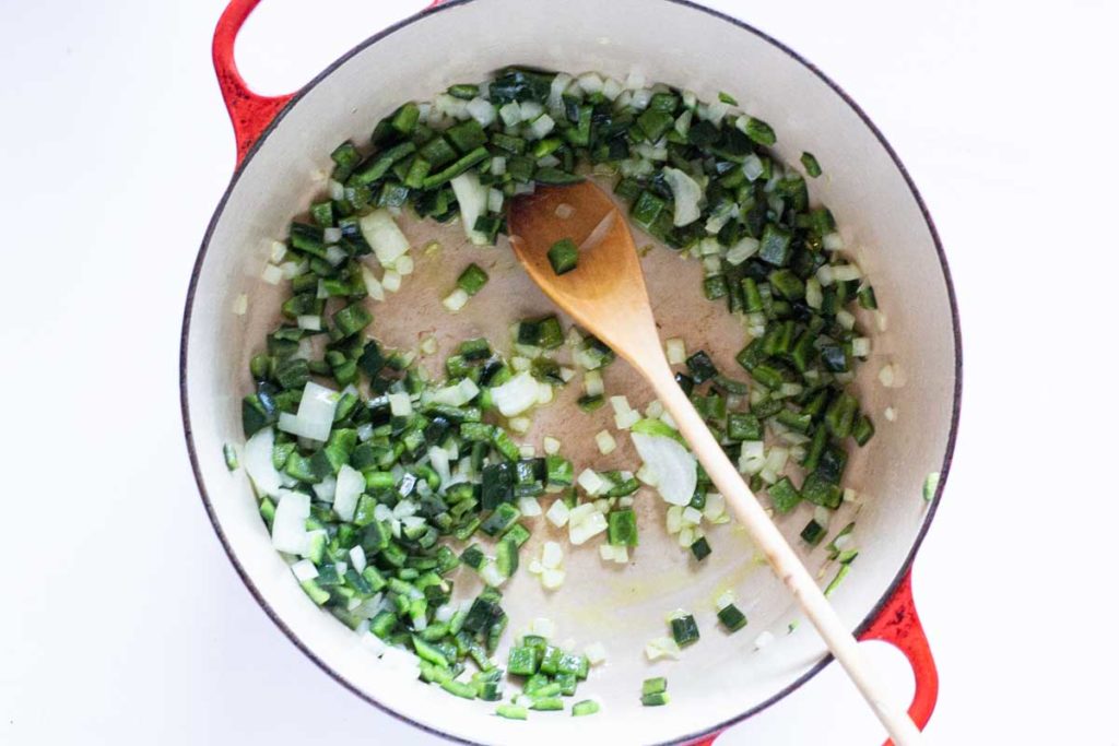 cooking poblano peppers and onions in a dutch oven.