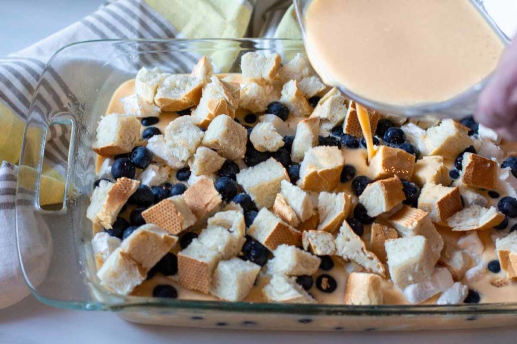 Pouring maple syrup over make ahead blueberry french toast casserole.