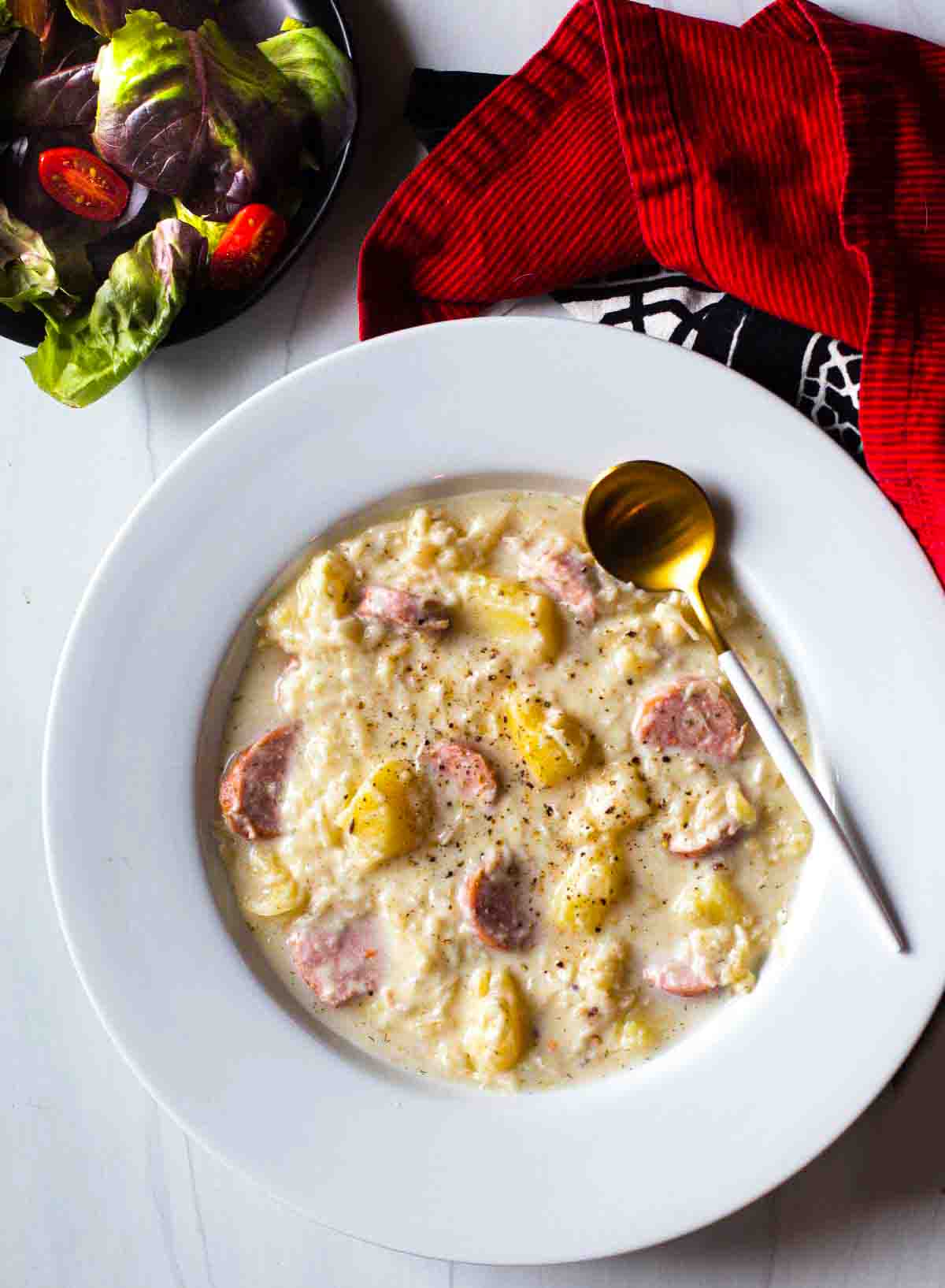 A bowl of creamy sauerkraut soup with sausage and potatoes