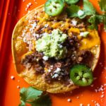 How to make a tostada with refried beans, chorizo, cheese and smashed avocado.
