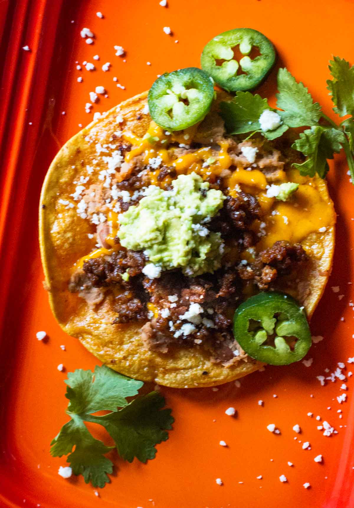 How to make a tostada with refried beans, chorizo, cheese and smashed avocado.