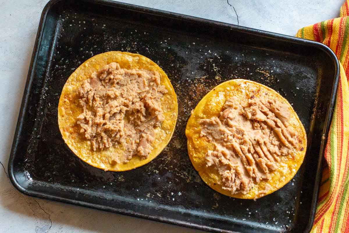 Two tostada shells topped with refried beans.