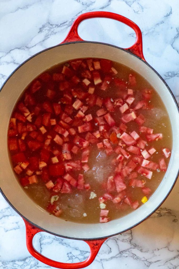 adding tomatoes to broth for chicken soup