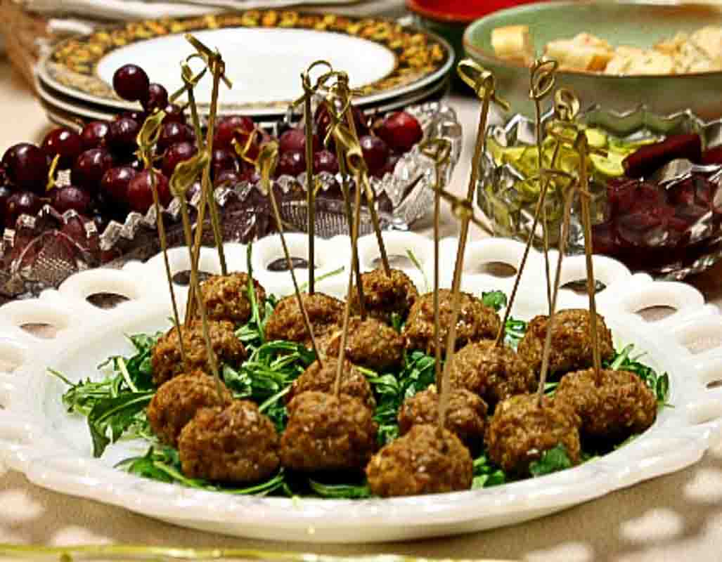 Spicy Lamb Meatballs on a bed of arugula on a white serving platter.
