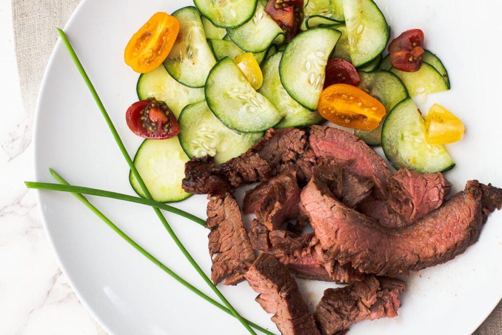 flank steak with asian marinade and cucumbers garnished with chives