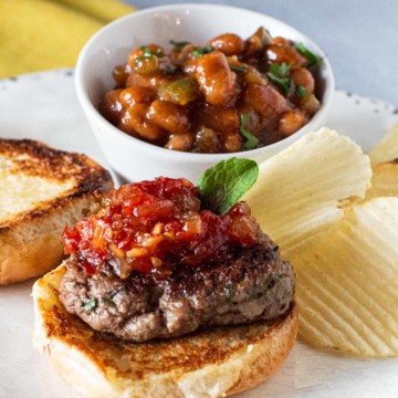 Lamb sliders topped with sweet tomato chutney and served with a bowl of baked beans.