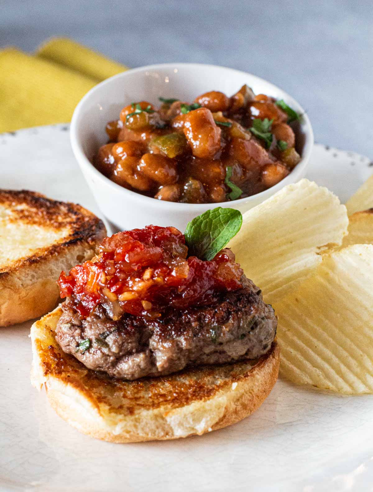 Lamb sliders topped with sweet tomato chutney and served with a bowl of baked beans.