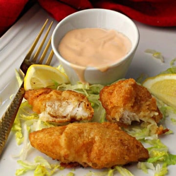 Marie Rose Sauce and pieces of battered cod on a bed of shredded iceberg lettuce with lemon wedges