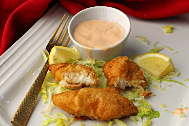 Marie Rose Sauce and pieces of battered cod on a bed of shredded iceberg lettuce with lemon wedges