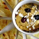 Yaya's hummus recipe topped with feta and olives served with slices of grilled pita