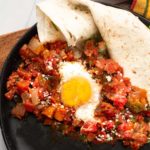 Easy huevos rancheros recipe with flour tortilla served with sauce