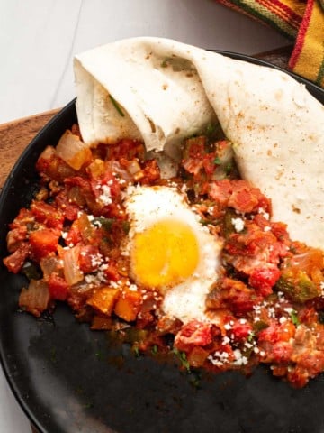 Easy huevos rancheros recipe with flour tortilla served with sauce