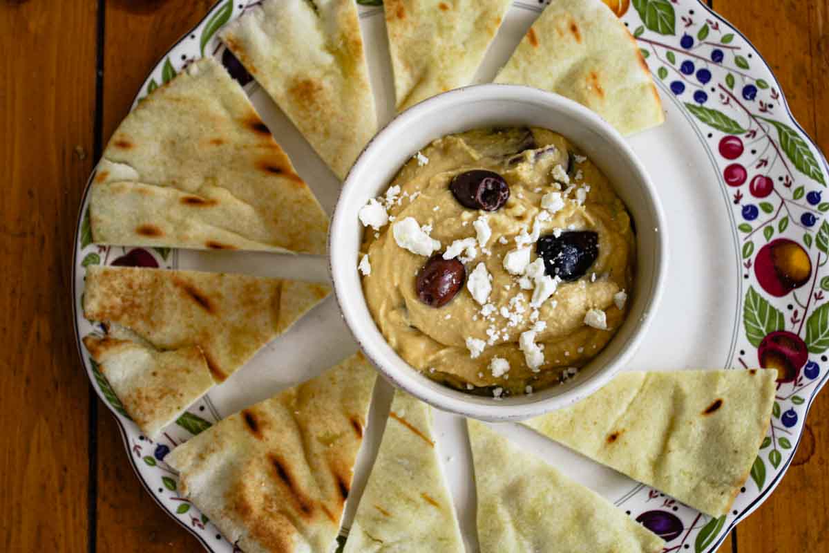 Hummus topped with olives and feta served with grilled pita wedges.