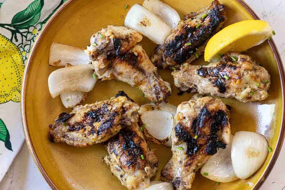 Cooked Limoncello Chicken Wings on a plate served with Vidalia onions.