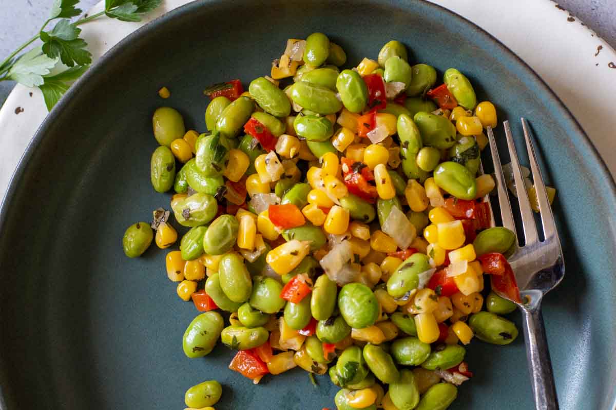 Sweet corn succotash with edamame served on a blue plate.