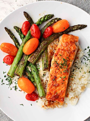 Salmon fillet glazed with mirin sweet cooking wine served over rice and sauteed asparagus and red and orange cherry tomatoes