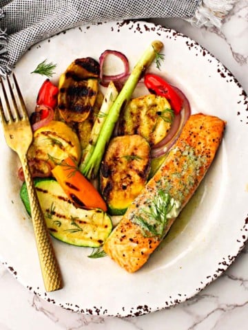 Grilled salmon fillet topped with dill butter served with grilled vegetables