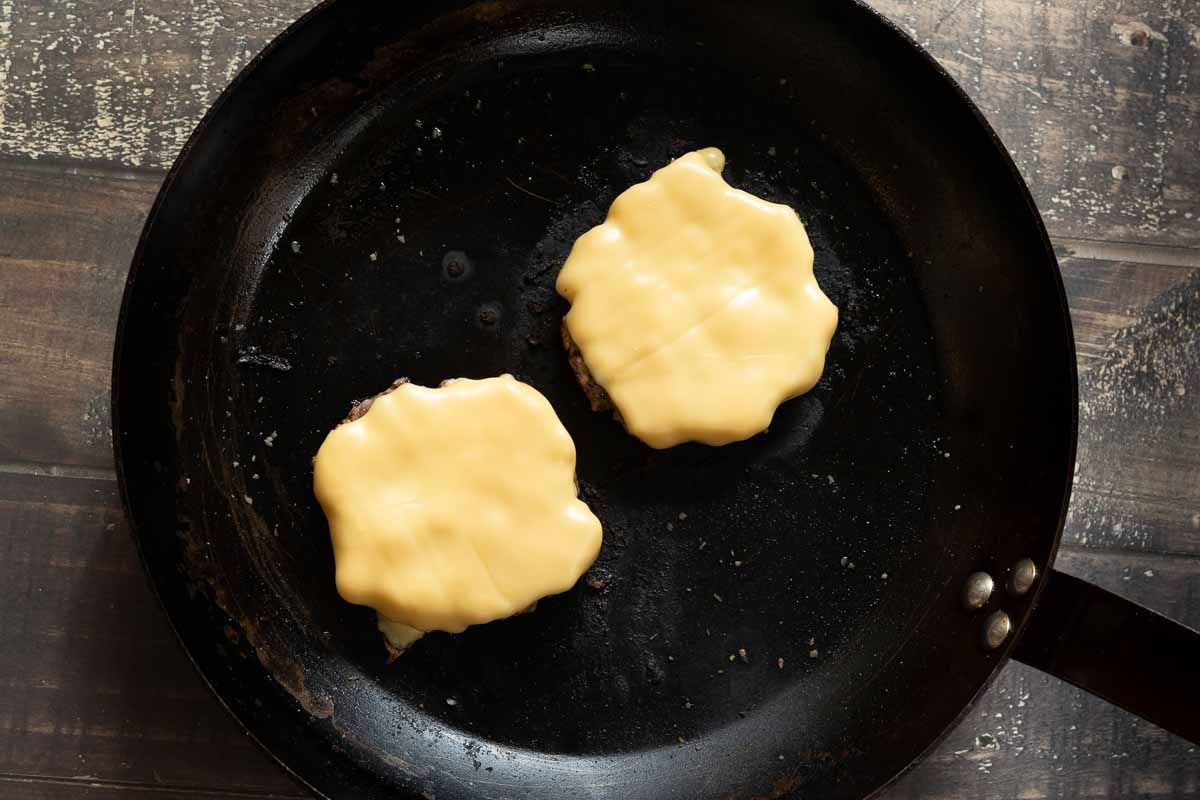 Pan fried green chile cheeseburgers with melted cheese.