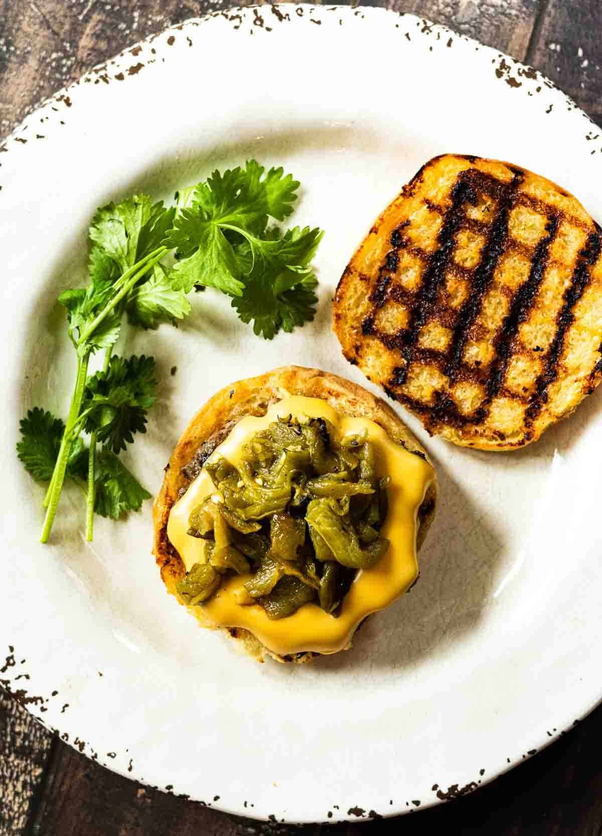 Green chile cheese burgers on a white plate.