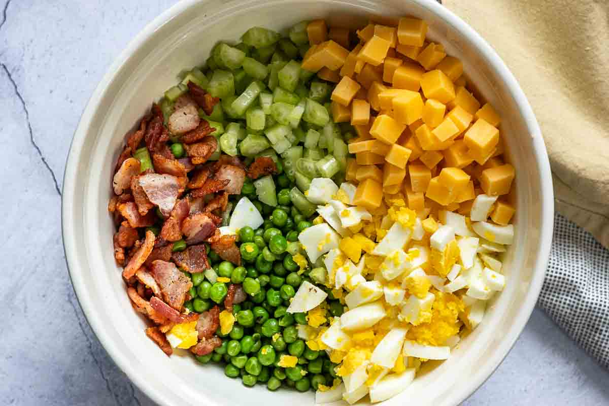Mixing ingredients in a bowl to make pea salad with eggs.