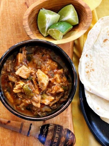 Hatch Green Chili With Pork served with flour tortillas and lime wedges