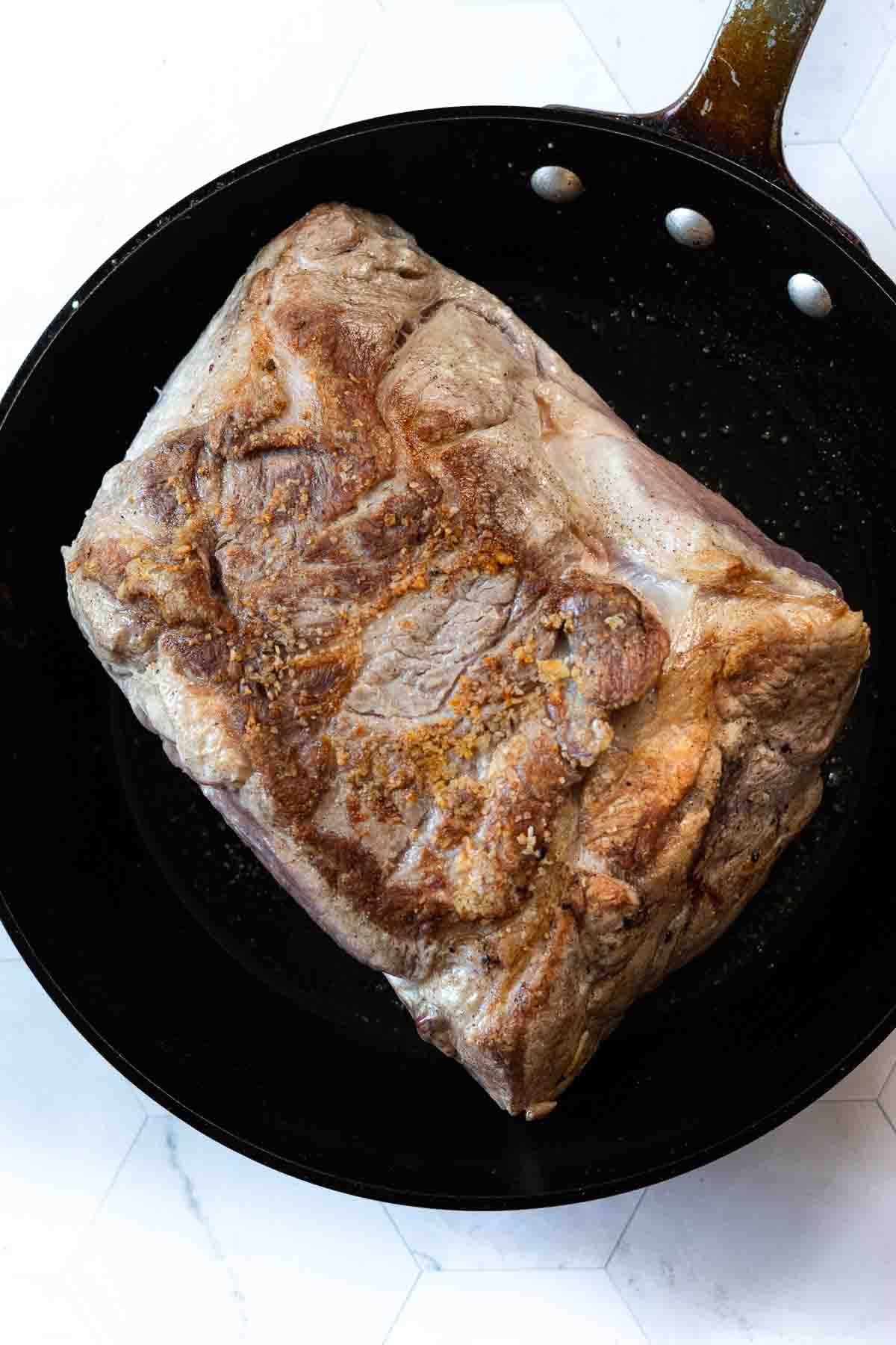 Searing a pork roast in a large skillet to make Hatch Green Chili.