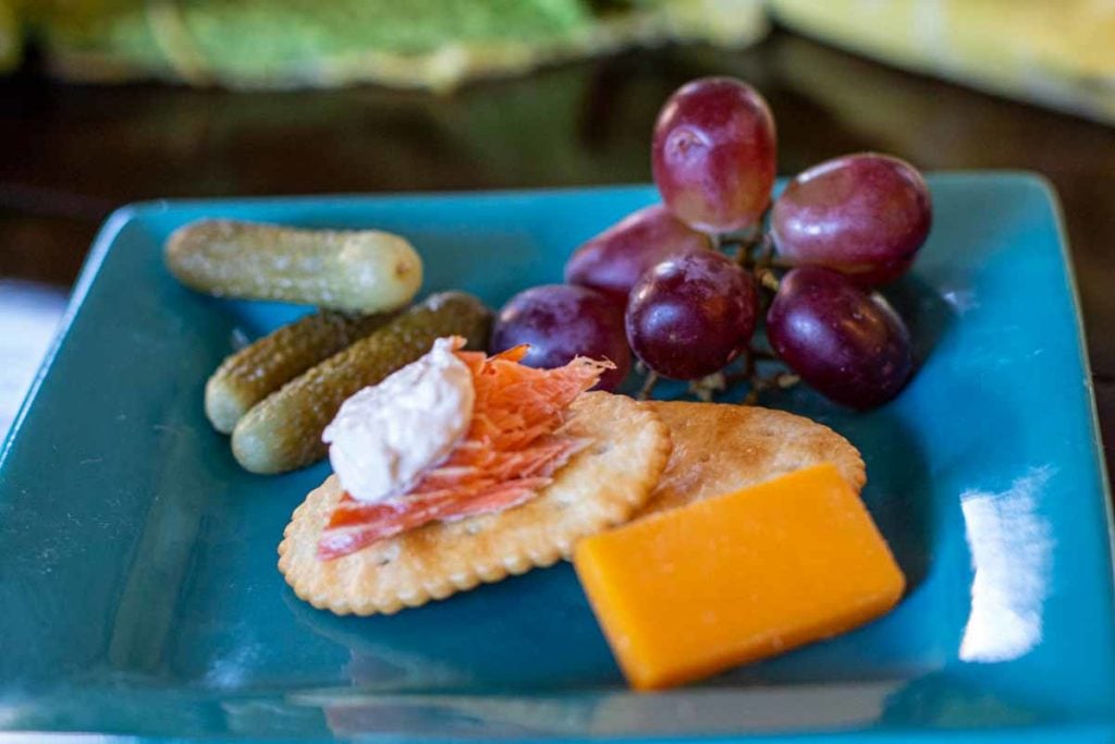 Cracker topped with smoked salmon, horseradish cream sauce with cheese, cornichons and grapes