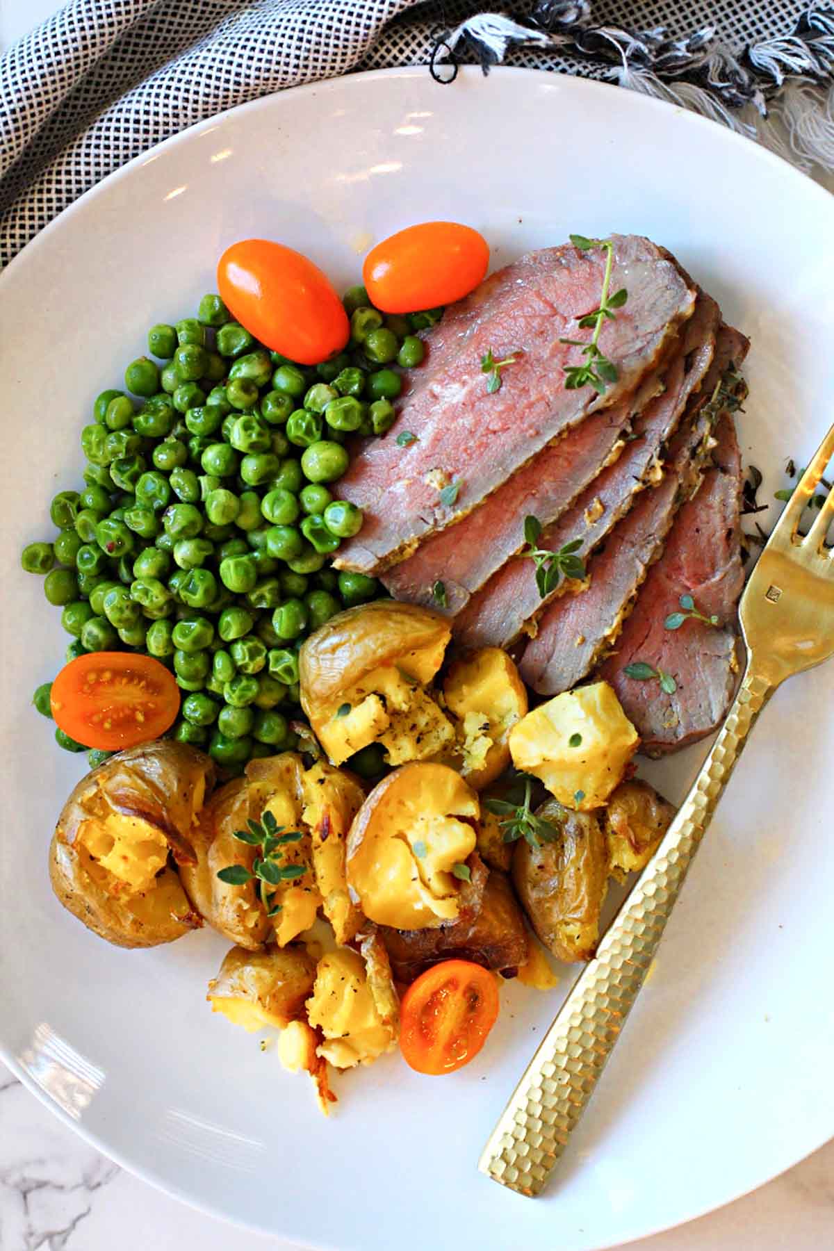 Baked tri-tip roast sliced and served with smashed potatoes and peas